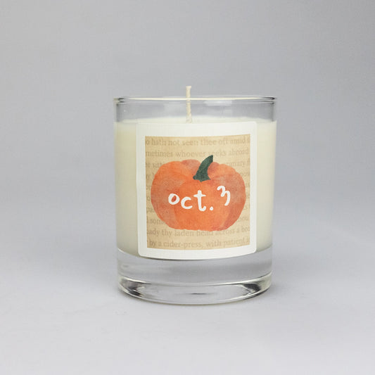 Product photo of scented soy candle Oct. 3, made by BONKI. Candle in glass jar. Beige label with orange pumpkin and writing "Oct. 3".